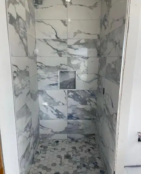Finished shower with marble tile and mosaic floor