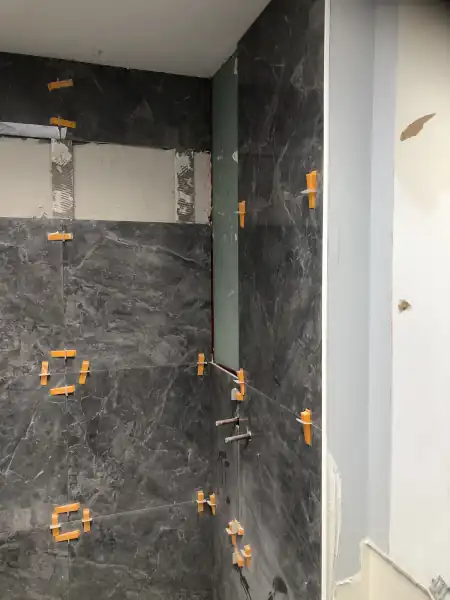 Dark marble tile shower installation