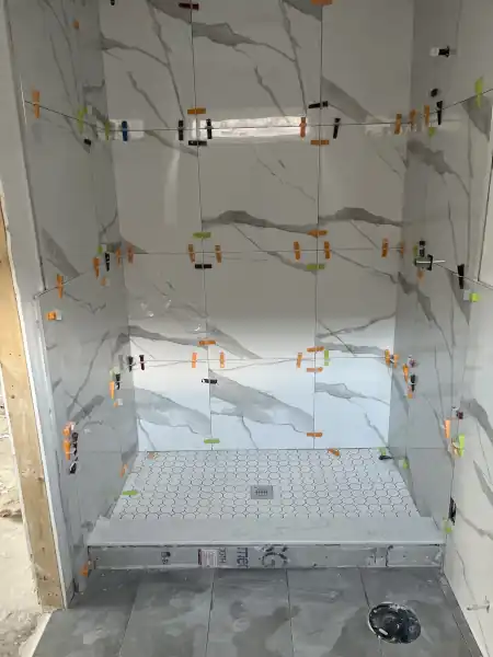 Finished small shower with mosaic tile floor and glass panel