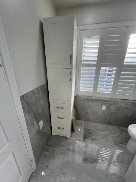 Naturally lit bathroom with grey marble-look tile and plantation shutters, installed by Munir Pro Tiles