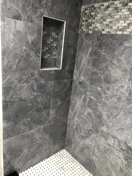 Finished marble tile shower with frameless glass enclosure